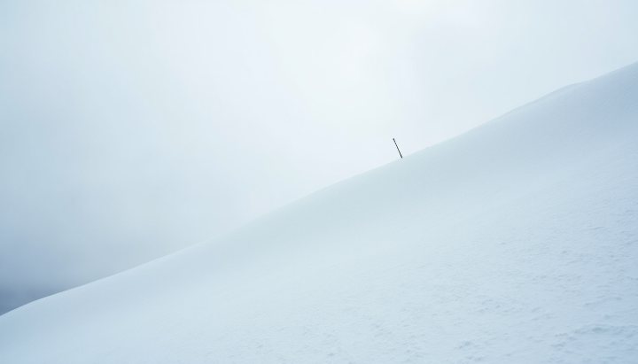 A groomed ski slope in flat overcast light where the surface texture is almost invisible